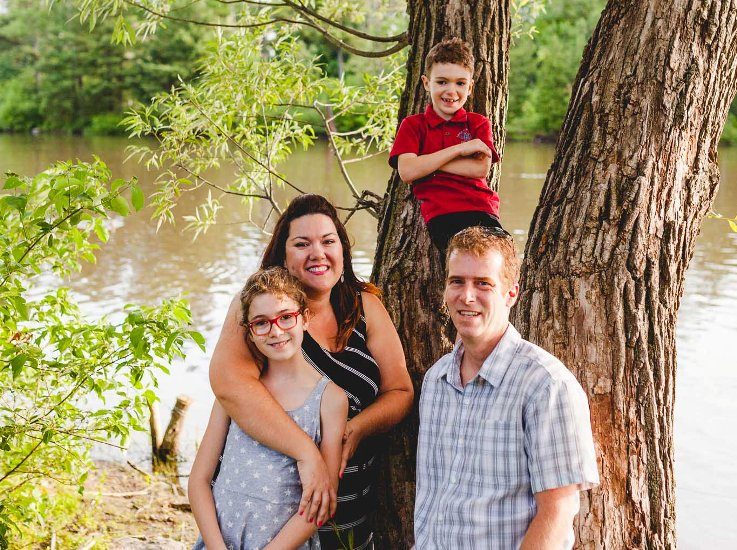 Magalie Lebrun, son conjoint et ses enfants posent près d'un arbre. 