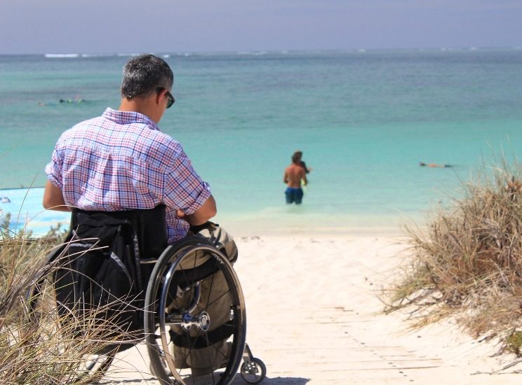 Homme en fauteuil roulant sur une plage près de la mer. 