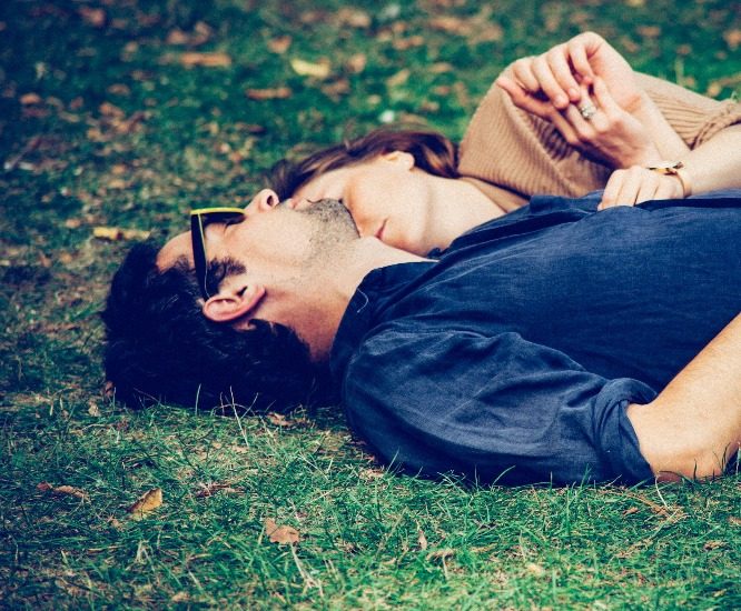 Un homme et une femme sont couchés dans la gazon.