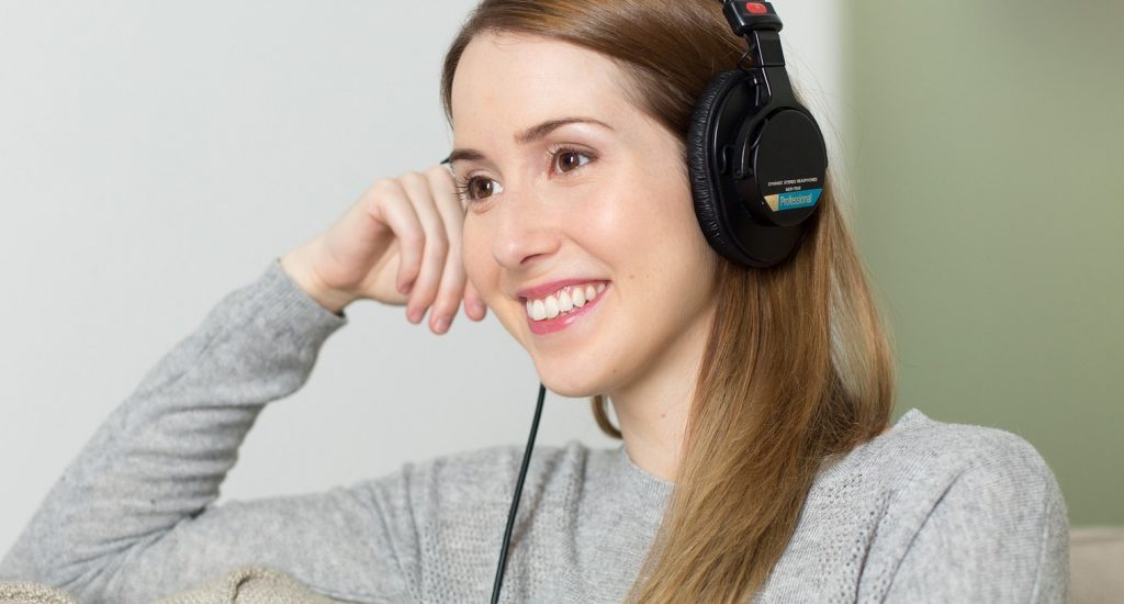 Une femme portant un casque d'écoute. Elle sourit.