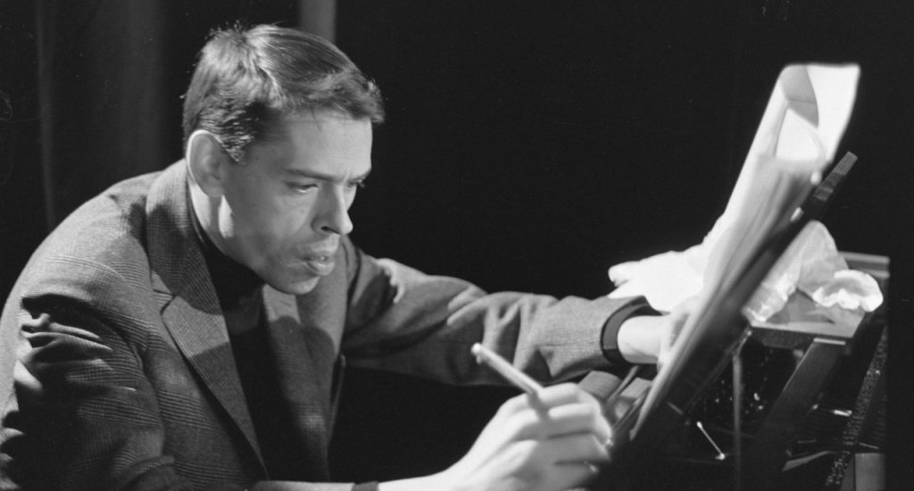 Jacques Brel, au piano, écrit sur une partition de musique. Jacques Brel, au piano, écrit sur une partition de musique.