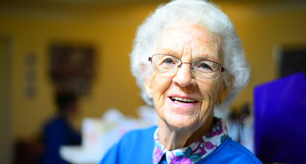 Une vielle dame aux cheveux blanc esquisse un sourire