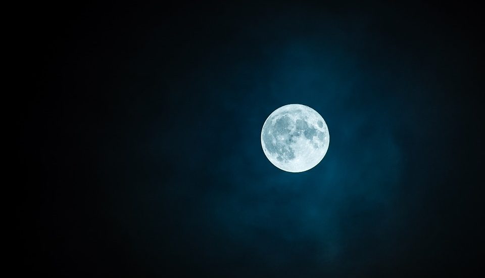 On aperçoit une pleine lune dans un ciel bleu noir. On aperçoit une pleine lune dans un ciel bleu noir.