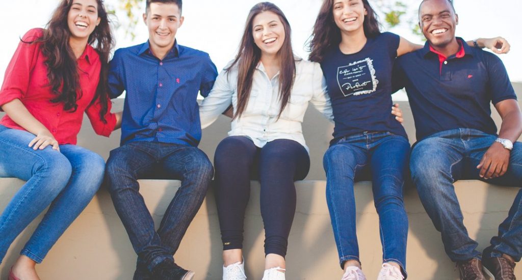 Jeunes adultes souriants (3 femmes et deux hommes). 