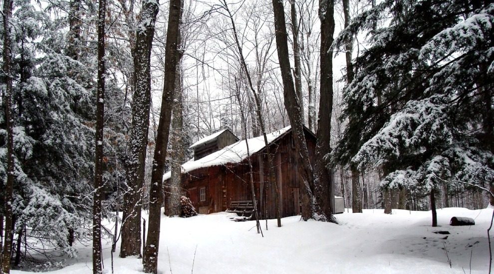 Une cabane à sucre traditionnelle en bois, dans la neige. 