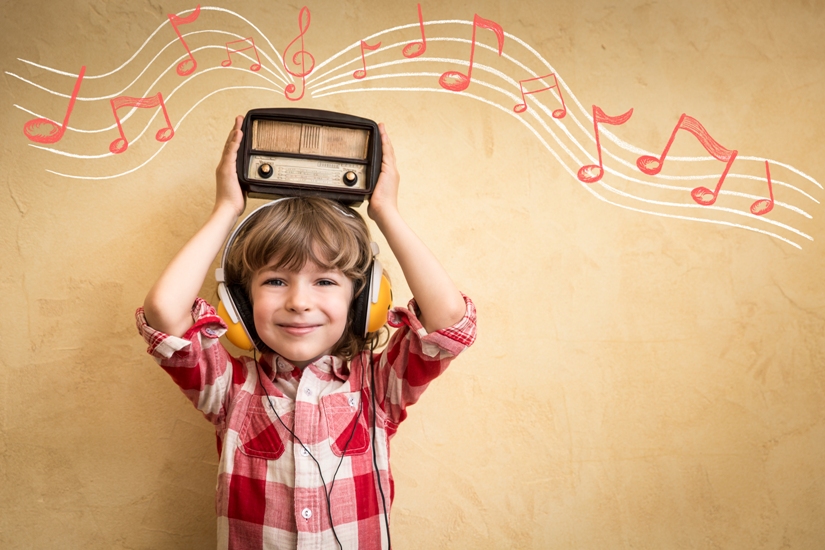 Une petit garçon tient une radio sur sa tête et il en sort une portée musicale et des notes roses et blanches. Une petit garçon tient une radio sur sa tête et il en sort une portée musicale et des notes roses et blanches.