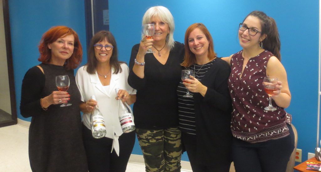 Arlette et ses invitées posent avec un verre de vin rouge. 