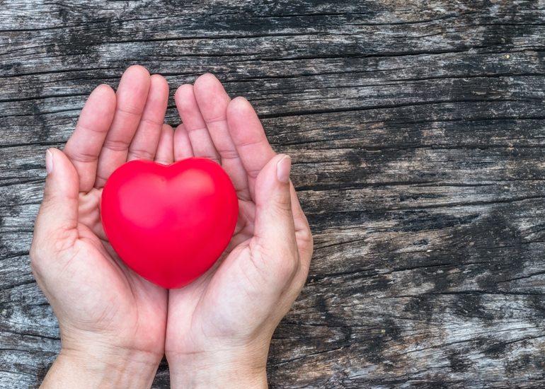sur un fond "planche de grange" des mains tiennent un beau coeur rouge