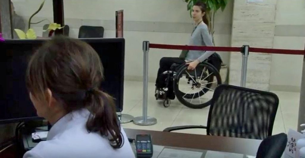 Une femme en fauteuil roulant se présente à la réception d'une clinique