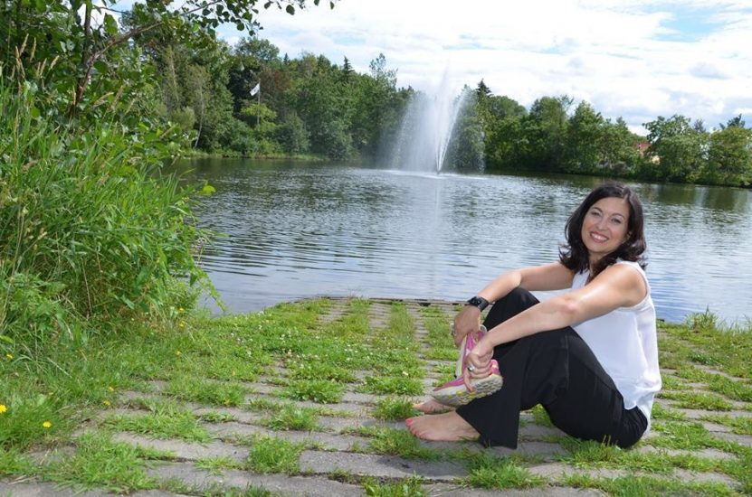 Chantal Dauray, assise devant une étendu d'eau, avec au loin une fontaine Chantal Dauray, assise devant une étendu d'eau, avec au loin une fontaine