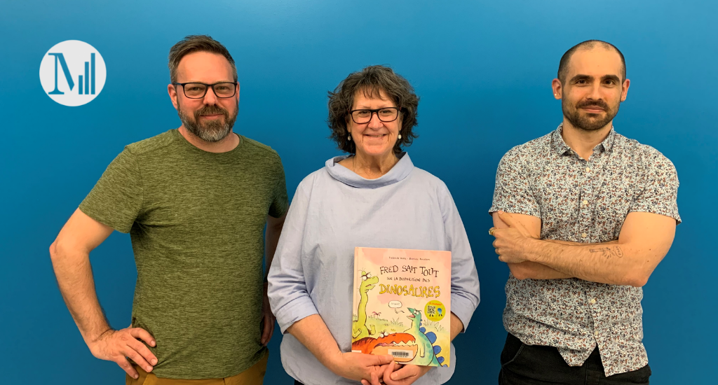 Au centre, l'animatrice Marie Lalande tenant le livre jeunesse Fred sait tout sur la disparition des dinosaures, entourée de l'auteur Frédérick Wolfe et de l'illustrateur Baptiste Amsallem. 