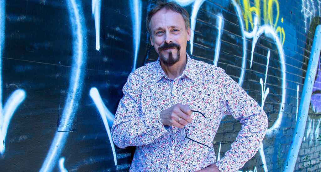 Denis-Martin Chabot pose devant un mur de graffiti. 