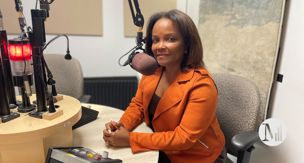 Marjorie Théodore est assise en studio avec une veste orange.