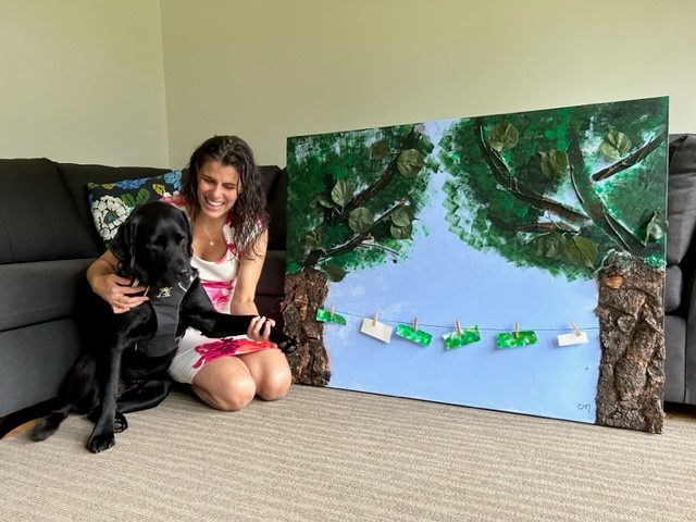 Claudia Nigrelli est à genou près de son chien noir et de l'une de ses peintures.