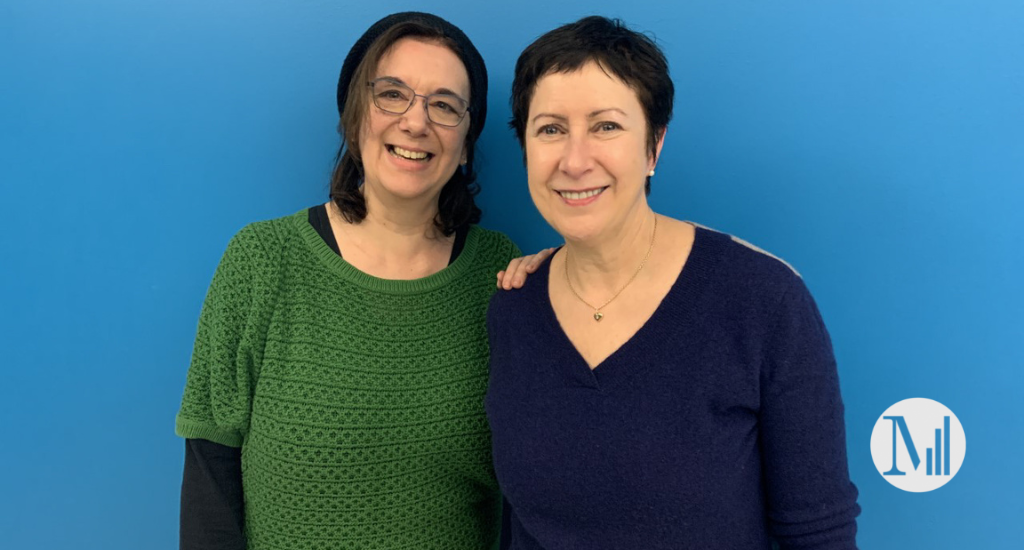 Hélène Denis et Marie Michaud posent devant un mur bleu.