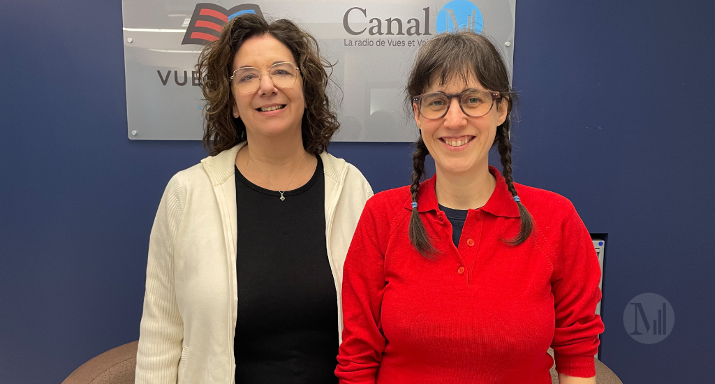 Sarah Berthiaume et Hélène Denis posent devant le panneau de Canal M Vues et Voix.