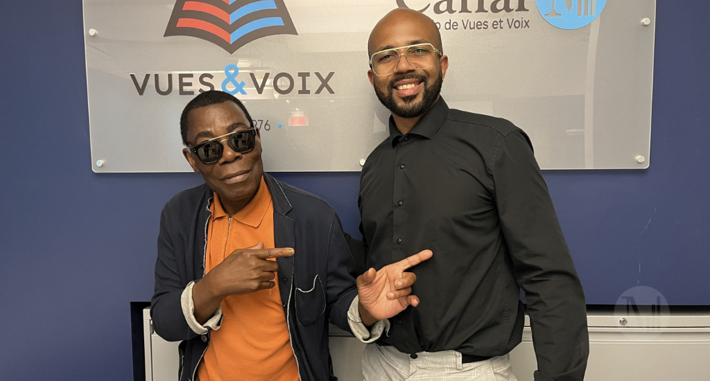 Dee Joyce et Fulgence Bla prennent la pose devant le panneau publicitaire de Vues & Voix. 