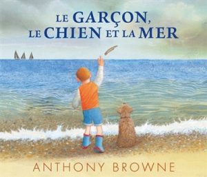 Le garçon, le chien et la mer. Un garçon et son chien regardent des voiliers à l'horizon.