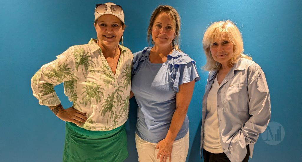 Nathalie Barrette, Annie Pelletier et Chantal Lavoie prennent la pose devant un mur bleu. 