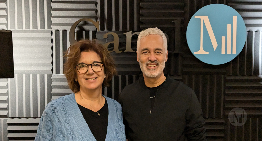 Hélène Denis pose avec Eric Jean devant le logo de Canal M en studio.