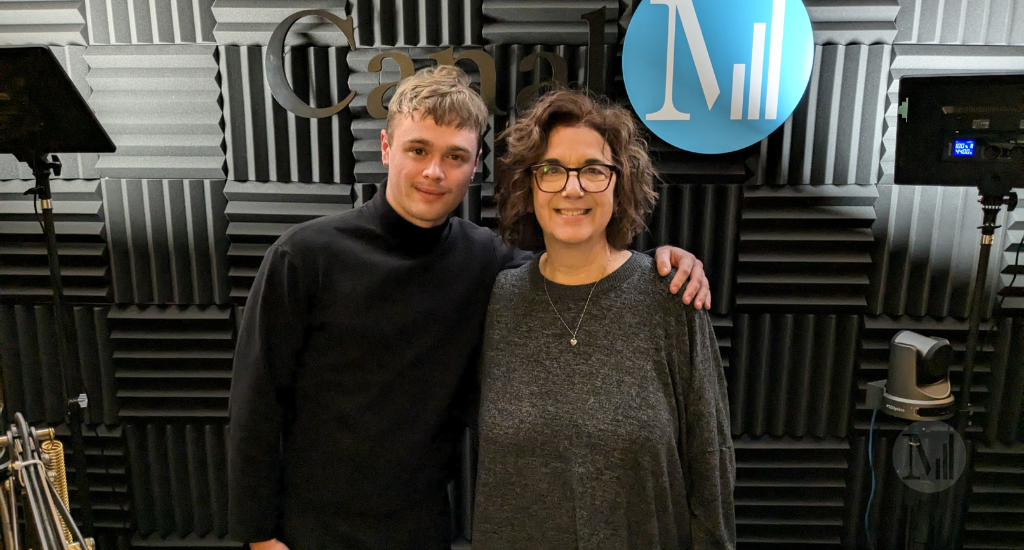 Noah Parker et Hélène Denis posent debout en studio près du logo de Canal M.